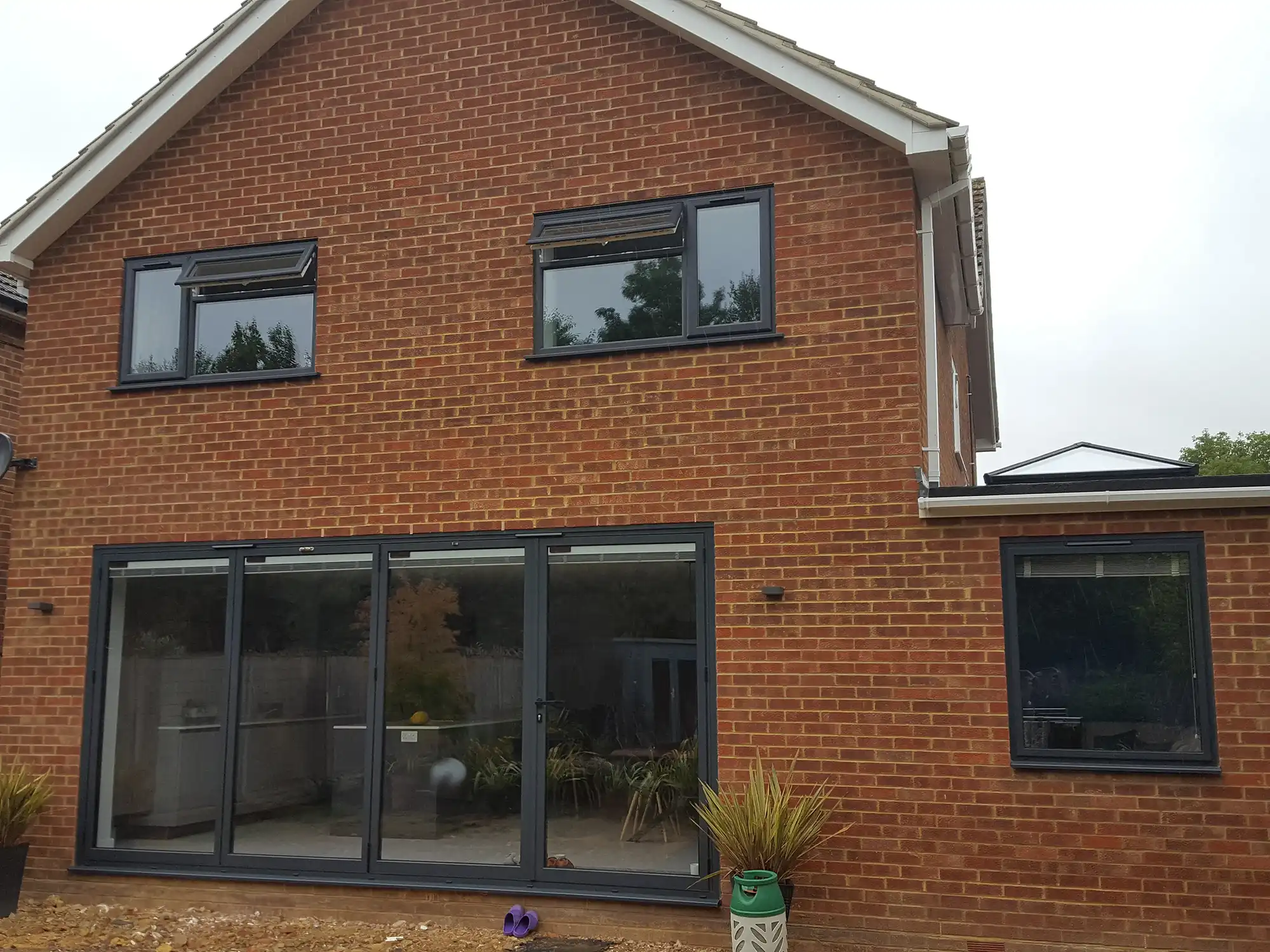 A brick house with two large windows on the side of it.