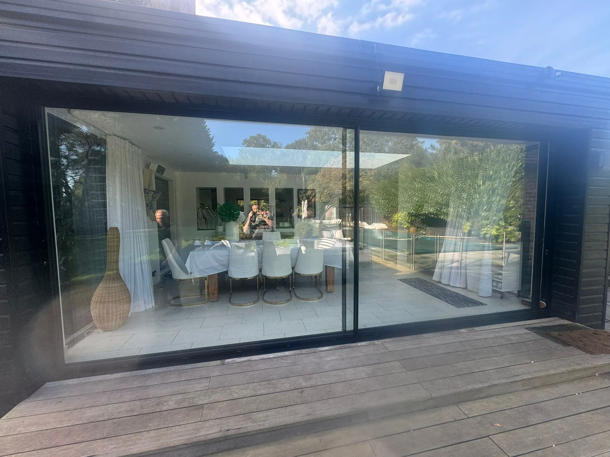 A person sitting at a table in front of a glass door.