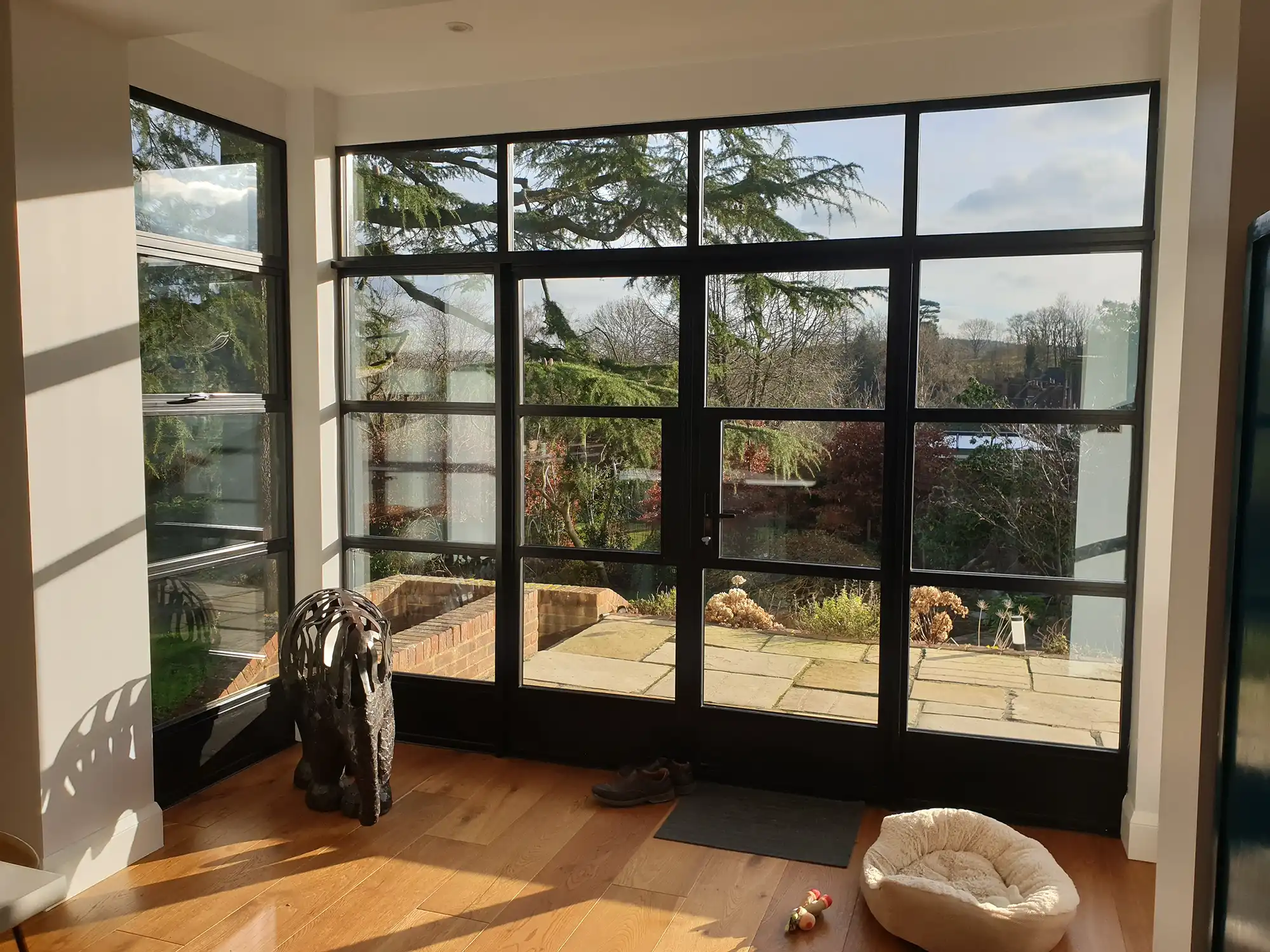 A room with a large window and a dog bed on the floor.